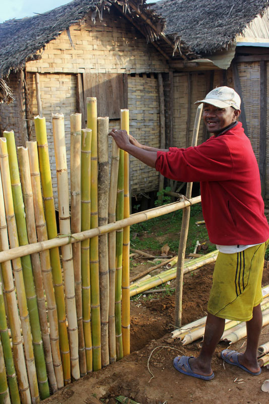 Een man bouwt een bamboehek